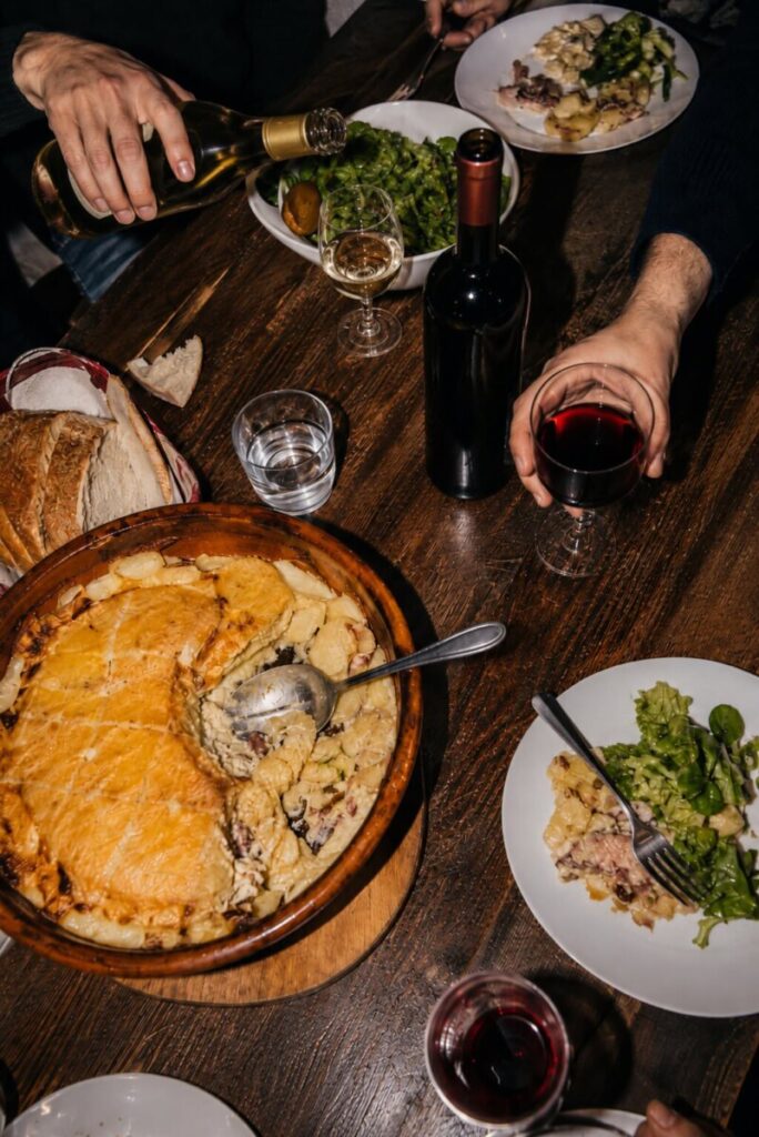 Tartiflette entre amis avec un vin blanc et un vin rouge sur la table